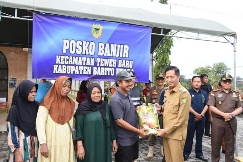 Pj Bupati Barito Utara Muhlis menyerahkan bantuan kepada warga terdampak banjir.(ist/Diskominfosandi Barito Utara)