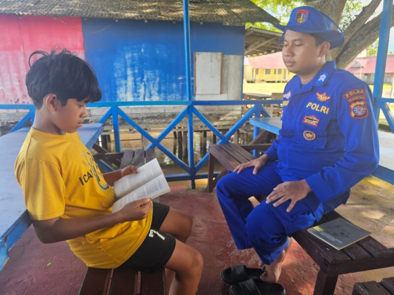 Anggota Ditpolairud Polda Kalteng membimbing belajar anak-anak yang berkunjung ke Kapal Melek Huruf (KMH) KP XVIII-2007 DAS Kapuas, Kabupaten Kapuas, Rabu, 22 April 2026.(Ist/Ditpolairud Polda Kalteng)

