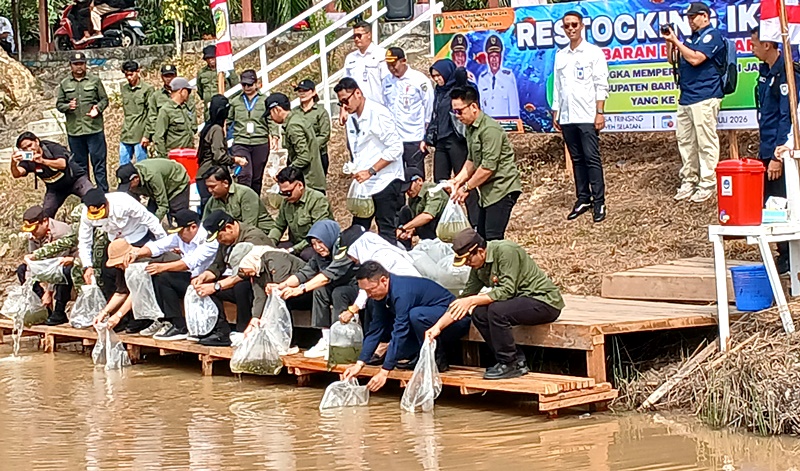 Bupati Barito Utara Shalahuddin didampingi Wabup Felix  SY. Tingan, Ketua DPRD Barito Utara, Forkopimda, ketua Komisi II DPRD, TP PKK, ketua GOW, dan kepala perangkat daerah menebar benih ikan di DAM Trinsing, Rabu, 22 Juli 2026.(Abram/Tegaklurus.net)
